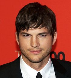 a close up of a person wearing a suit and tie on a red carpeted background