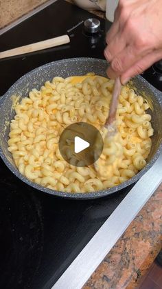 a person is stirring macaroni and cheese in a skillet on the stove