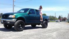 a woman sitting on the hood of a green pick up truck