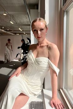 a woman in a white dress sitting on a window sill