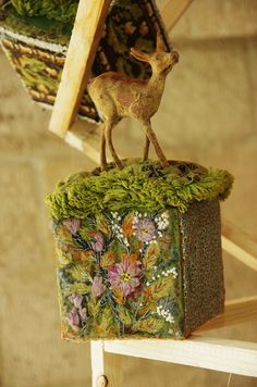 a deer figurine sitting on top of a moss covered box in a room