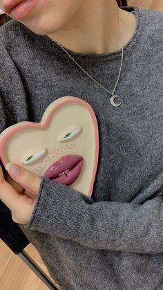 a woman holding a ceramic heart shaped object