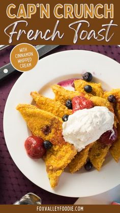 a white plate topped with french toast covered in whipped cream and fruit next to a fork