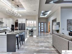 a large open concept kitchen and living room with high ceilings, tile flooring and stainless steel appliances