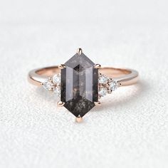 an engagement ring with a black diamond and three white diamonds on the band, set in 18k rose gold