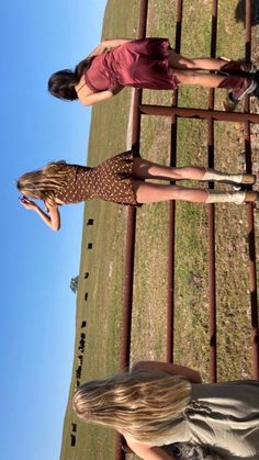 two women standing next to each other on a field with grass and blue sky in the background