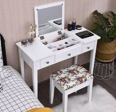 a white vanity table with drawers and a stool next to it on top of a bed