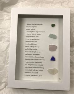 a white frame with five different colored rocks in it and a poem printed on the back