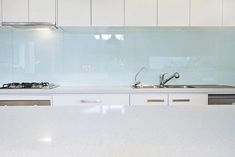 a white counter top sitting next to a stove top oven under a glass backsplash