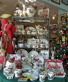 a table topped with lots of christmas themed dishes and cups next to a teddy bear