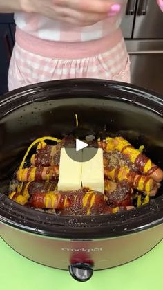 a crock pot filled with food sitting on top of a green counter next to a woman