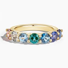 a yellow gold ring with five different colored stones on the side and two rows of blue,