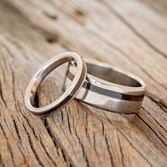 two wedding rings sitting on top of a wooden table