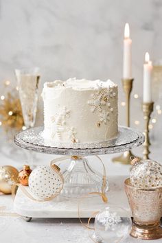 a white frosted cake sitting on top of a table next to candles and ornaments