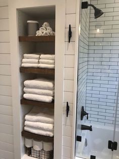 towels are stacked on shelves in the bathroom