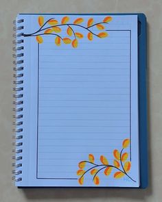 an open spiral notebook with yellow leaves on blue lined paper, sitting on a table