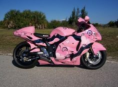 a pink motorcycle is parked on the side of the road