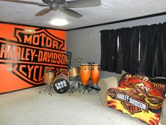 an orange and black room with guitars, drum heads, and other musical instruments