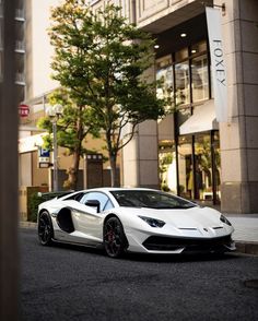 a white sports car parked in front of a tall building