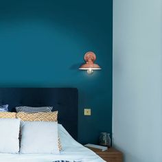 a bed with blue walls and white pillows in a room that is painted teal