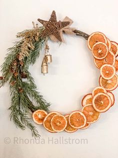 orange slices arranged in the shape of a wreath with bells and pine cones on top