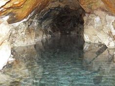 a pool in the middle of a cave with water flowing from it's sides