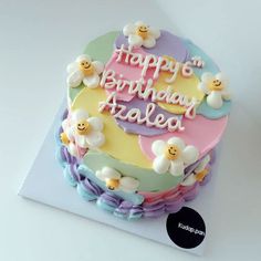 a birthday cake with flowers and smiley faces on it