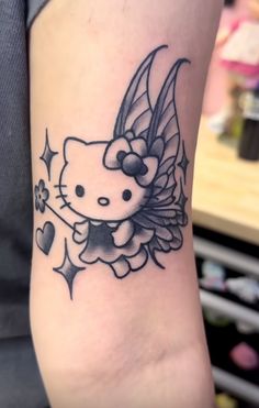 a hello kitty tattoo on the arm with hearts and wings around it's head