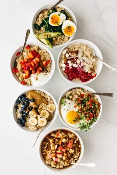 six bowls filled with different types of food on top of a white countertop next to utensils