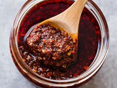 a wooden spoon filled with chili sauce on top of a table