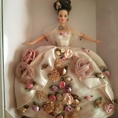 a barbie doll dressed in a white dress with pink flowers on it's skirt