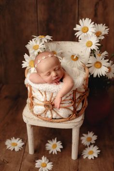 a baby is laying in a chair with daisies