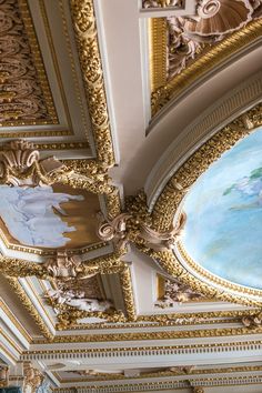 an ornate ceiling with paintings on it in a room filled with gold and white walls