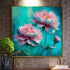 pink flowers are displayed in front of a painting on the wall above a wooden table