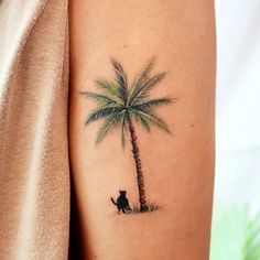 a cat sitting under a palm tree tattoo on the left side of the right arm