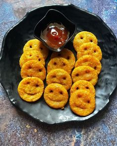 a black plate topped with crackers and ketchup on top of a table