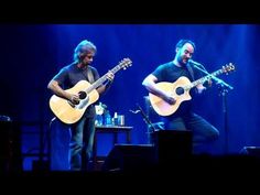 two men are playing guitars on stage