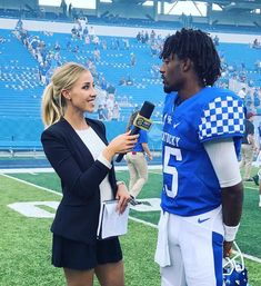 a woman talking to a football player on the sidelines at a game with a microphone in her hand