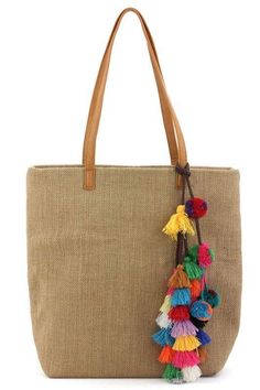 a tan tote bag with colorful tassels hanging from it