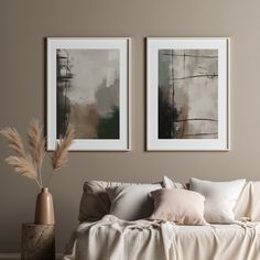 two paintings hang on the wall above a bed with white sheets and pillows, next to a vase filled with dry grass