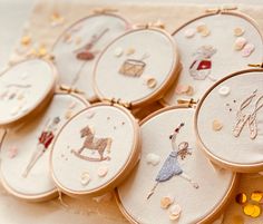 several embroidery hoop frames with different designs on them and some buttons in the middle one