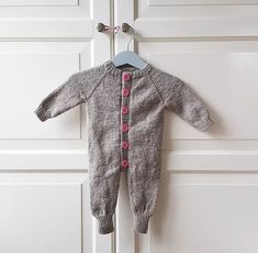 a baby's gray and pink knitted footie hanging on a white door