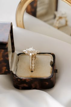 an engagement ring sits in front of a mirror