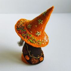 an orange hat is sitting on top of a small black pot with leaves and stars