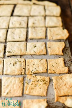 homemade crackers with herbs on them sitting on a baking sheet, ready to go into the oven