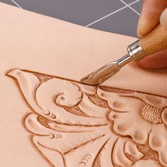 a person using a pen to draw an ornate design on a piece of paper with wood