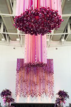 a large chandelier hanging from the ceiling in front of a stage decorated with purple flowers