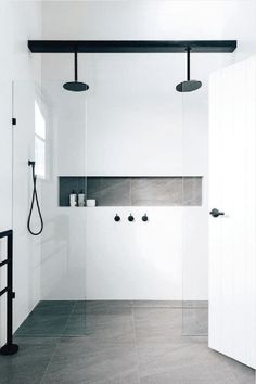 a bathroom with black and white fixtures, tile flooring, and an open shower