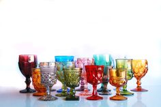 many different colored glasses lined up on a table