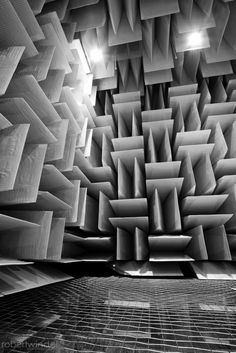 black and white photograph of an abstract building with many square openings in the ceiling,